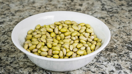 Bowl filled with dried Canary beans on a granite countertop showcasing their natural colors and textures