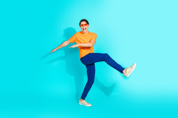 Energetic Young Man in a Bright Outfit Striking a Fun Pose Against a Vibrant Turquoise Background