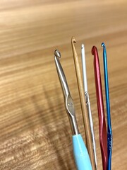 Assorted crochet hooks on wooden surface: metal and wooden tools for crafting National Crochet Month