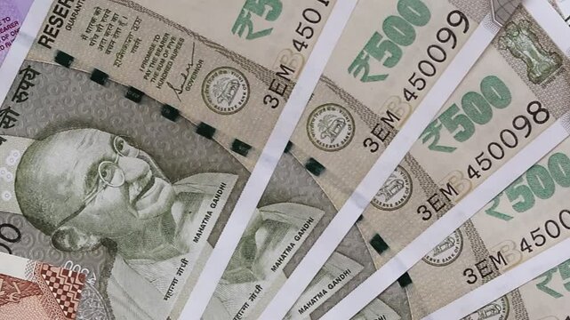 Panoramic top view of Indian banknotes of 10, 50, 100 and 500 indian rupees laying on the table surface. Close-up slow motion video