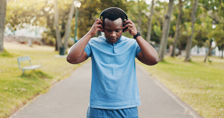 Headphones, music or black man in park for running, training exercise or workout for fitness. Outdoor, African athlete and healthy male runner listening to sports podcast, motivation or radio audio