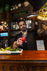 Bartender pouring cocktail in irish tavern with shaker