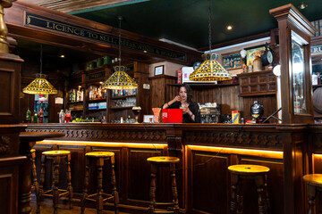 Barmaid preparing drinks in traditional irish pub