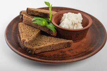 Traditional rural dish with slices of dark rye bread, spread with lard and fresh parsley on a ceramic plate. Authentic Eastern European cuisine close-up, top view, side view