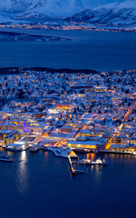 closeup aerial view of Tromsø at blue hour beautiful yellow lights, surrounded by dark blue sea
