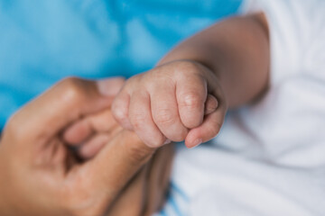 Newborn baby holding nurse finger, postpartum healthcare