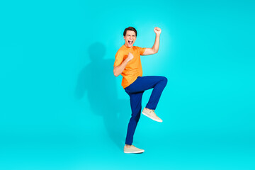 Happy young man in casual outfit celebrating with an excited expression against turquoise background, vibrant energy