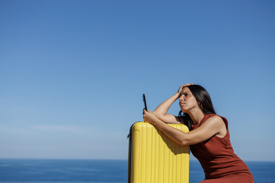 Young woman seriously looks at her mobile phone to search for offers from travel agencies, dream places... Concept of online sales, purchase, travel insurance, problems on the trip, requesting help.
