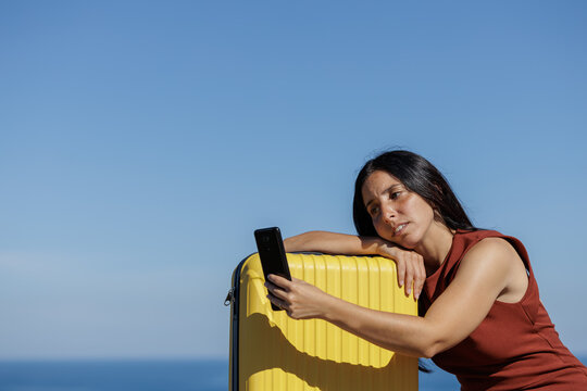 Young woman seriously looks at her mobile phone to search for offers from travel agencies, dream places... Concept of online sales, purchase, travel insurance, problems on the trip, requesting help.