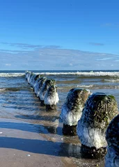 ice on the frozen wooden groynes on Baltic Sea in winter season with blue sky