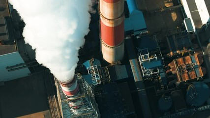 Air pollution from a coal power plant in operation emitting smoke into the atmosphere near an industrial area