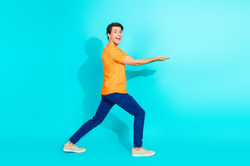 Young man in vibrant outfit gesturing and showcasing on a turquoise studio background