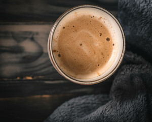 Cremiger Kaffee mit Schokoladenaroma auf dunklem Holzuntergrund mit grauer Decke