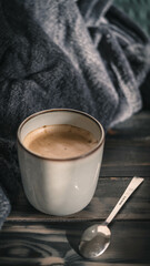 Cremiger Kaffee mit Schokoladenaroma auf dunklem Holzuntergrund mit grauer Decke