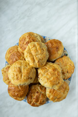 A plate filled with freshly baked golden brown scones sits on a marble countertop. 