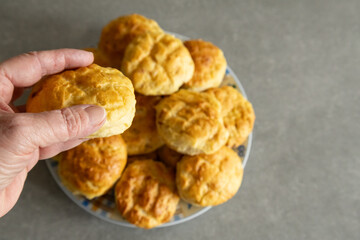 A hand holding a golden brown homemade scone.