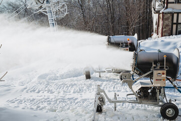 In a picturesque snowy area, a large machine efficiently blows snow, creating an enchanting flurry of sparkling white flakes, beautifully painting a stunning picture of a winter wonderland