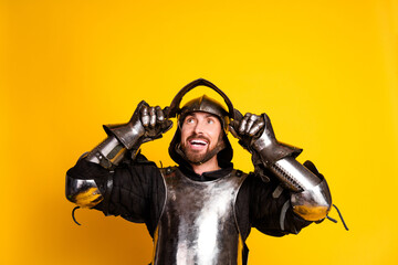 Young man wearing knight armor with a bright expression on a vivid yellow background