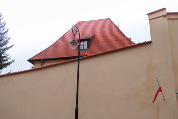 Red tile roof with small window. street lamp in front of house, flag at entrance. architecture, design