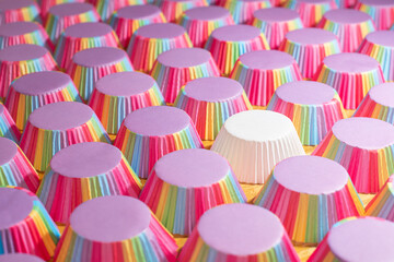 Single white muffin cup among rainbow cups. Stand out from the crowd concept