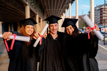 Obraz premium Group of cheerful multi ethnic graduates celebrating their graduation day showing their diplomas