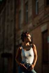 Portrait of a girl in summer on the street in a white T-shirt and curlers on her head