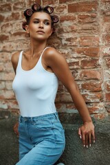 Portrait of a girl in summer on the street in a white T-shirt and curlers on her head