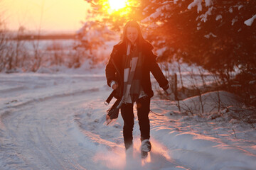 young woman walking in a snowy winter forest at sunset. dressed in a black leather jacket and a checkered shirt. frosty weather in a pine forest. lots of snow and sun. Christmas holiday