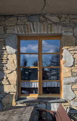 Okno z odbiciem drzew w szybie, ściana do okoła okna zbudowana z kamienia © Stefan