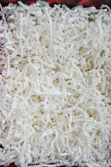 White corrugated shredded paper for filling gift boxes and baskets. Concepts of backgrounds, gift and decorative papers. Horizontal texture close-up.