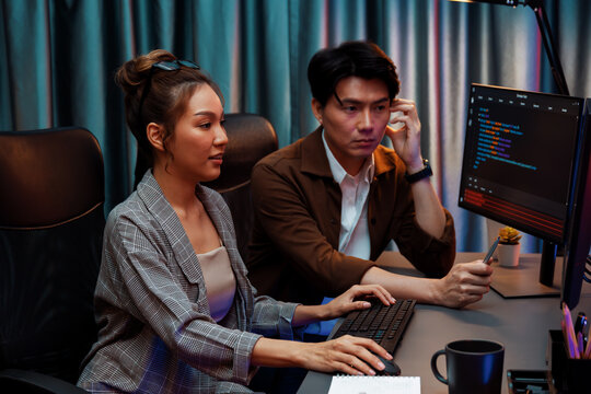 IT developers discussing with point to intelligent website development coder system running data online two screens information technology at neon light room at modern office. Infobahn.