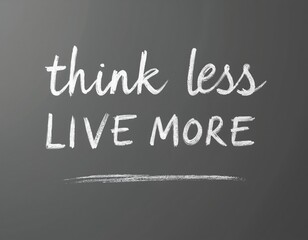 Obraz premium Think less live more motivational message written in white chalk on dark gray wall. Inspiring, optimistic philosophy banner concept about enjoyment, freedom, happiness, inspiration. Success text.