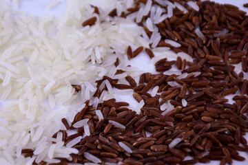 A mixture of white and brown rice, scattered grains on a white background.