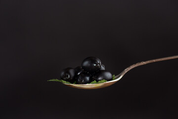 black olives in a spoon isolated on a black background