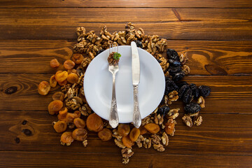 Clean empty plate and Nuts, dried apricots and prunes on a wooden table