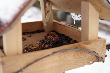 A close-up photo of a bird feeder containing birdseed and a suet ball.