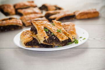 Golden puff pastries with mushroom filling and sesame seeds, on a light wooden table