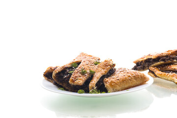 cooked puff pastries with mushroom filling and sesame seeds in a plate, isolated on white background