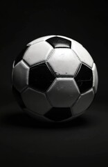 Naklejka premium Detailed black, white soccer ball image. Classic football sport equipment on dark background. Round leather ball shows iconic competition symbol. Monochrome photo featuring traditional game