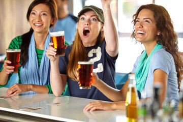 Celebration, beer and women in pub with cheers, game goal and sports for support together. Excited, happy hour and group of friends with alcohol, drink and broadcast television for team match in bar