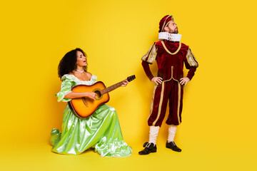 Elegant Couple Performing in Renaissance-Inspired Costumes Against Bright Yellow