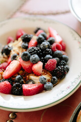 Fresh berry and fruit bowl served on a table with a delicate floral design during breakfast time