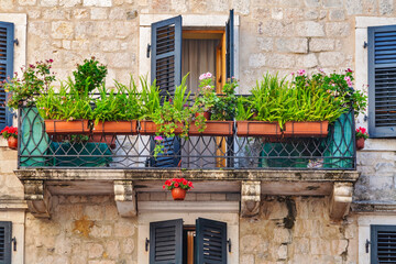 Old windows and balconies in old stone wall with plants