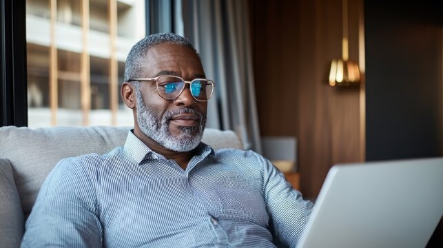 A man sitting alone at home working or studying on his laptop. - Powered by Adobe