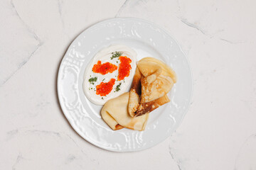 Pancakes with cream sauce and salmon caviar