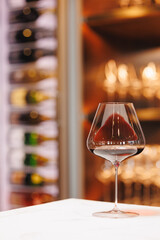 A glass of red wine on the background of a wine refrigerator.