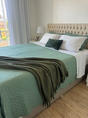 cama arrumada em tons verdes 