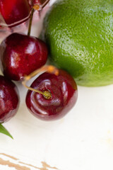 Fresh cherries and a lime on a white surface