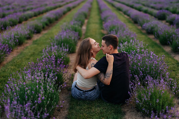 young couple in love man and girl on a walk on the street in nature under the open sky hugging and kissing. Lavender field with purple flowers for a romantic couple of people in love