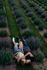 young couple in love man and girl on a walk on the street in nature under the open sky hugging and kissing. Lavender field with purple flowers for a romantic couple of people in love